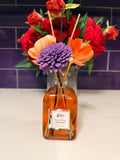 Bottle of diffuser oil with a bouquet of flowers on a tiled wall background